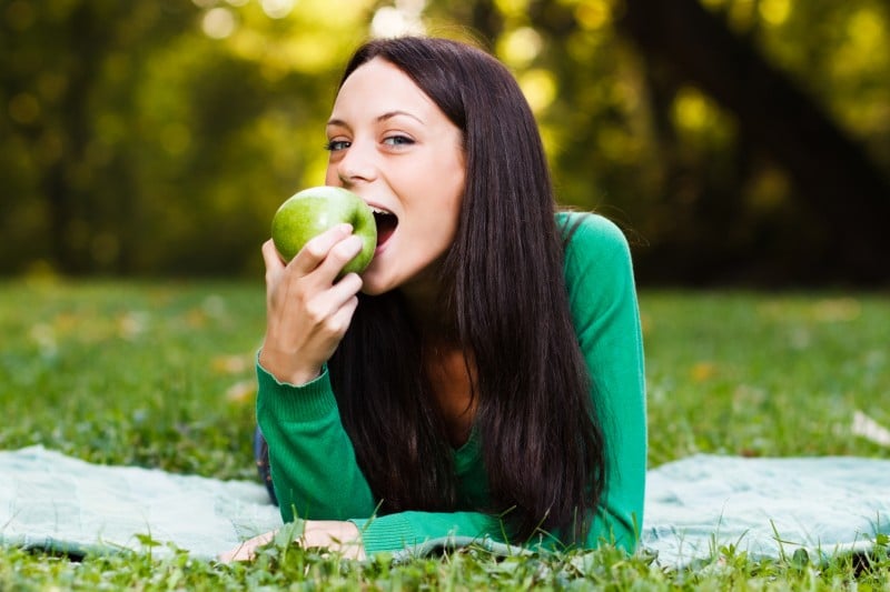 Woman eating an apple at a picnic in the park
