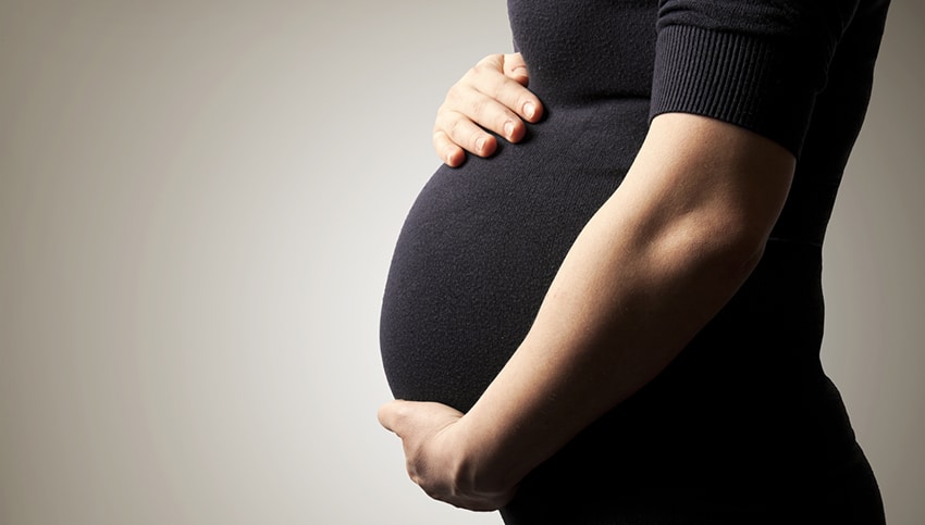 Belly of pregnant woman on brown background