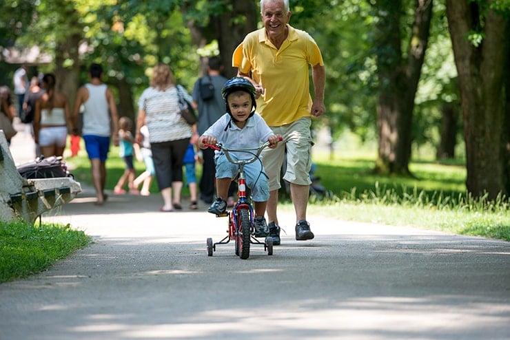 grandfather running after his grandson riding a tricycle