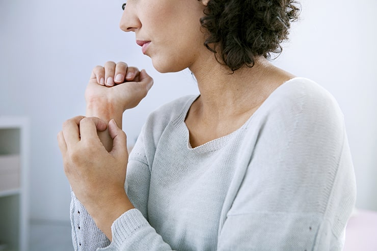 Woman itching arm. Psoriasis and Gum Disease may be linked