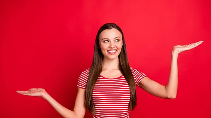 Charming girl holds up her hands, weighing her options for teeth whitening