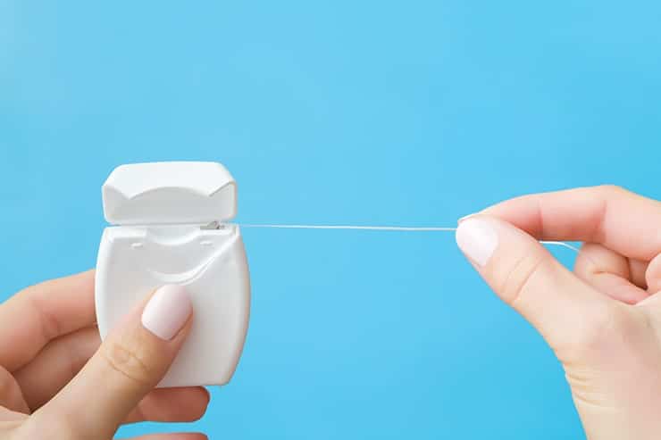 A female hand pulling floss out of a white container