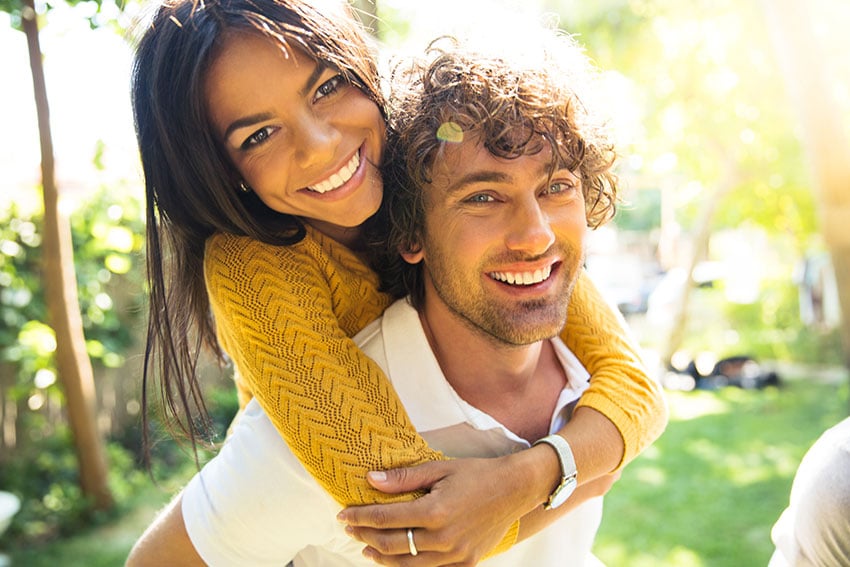 young man giving girlfriend a piggy back ride on a warm day