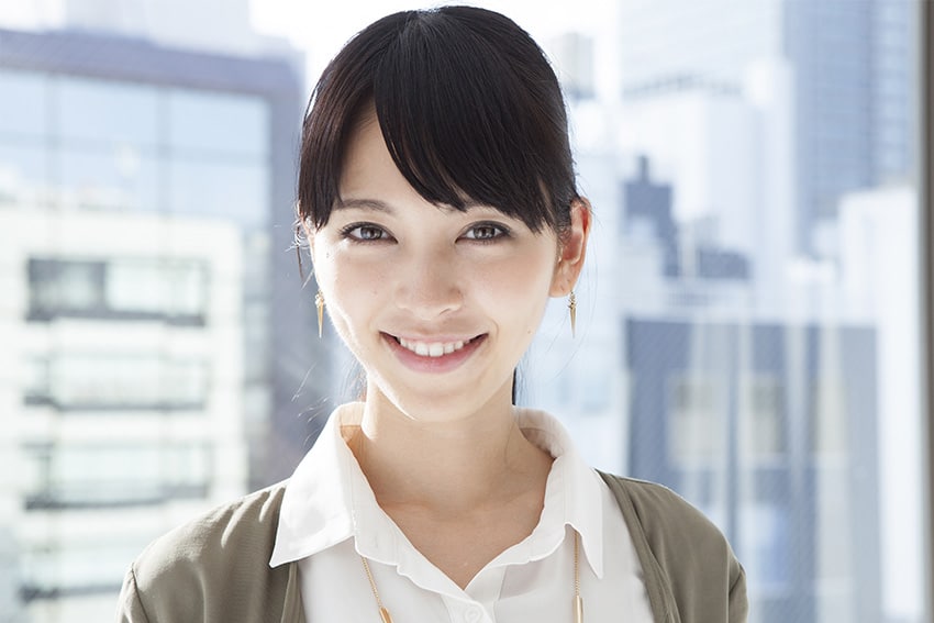 attractive Asian woman in sweater shows off her smile