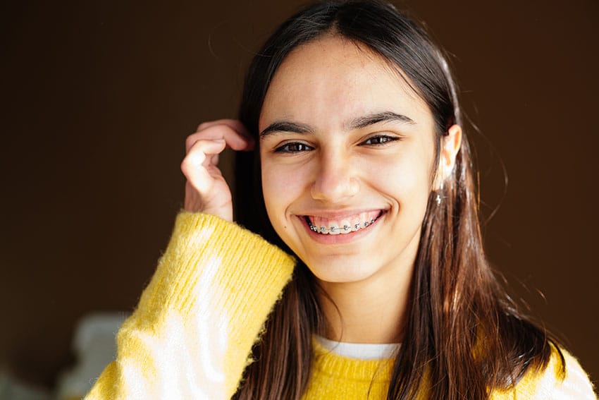 cute young woman with metal braces shows off her smile