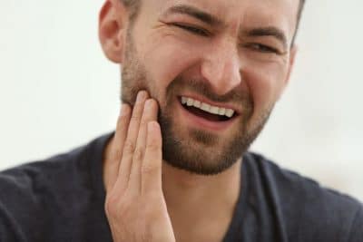 adult man holding his jaw in pain
