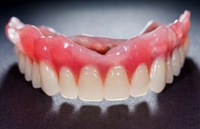 A close up of dentures with a dark background.